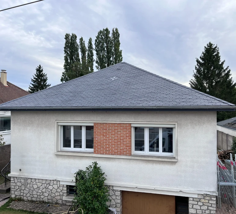 Maison individuelle vue de l'extérieur, façade enduit blanc avec encadrement de fenêtres en brique rouge apparente