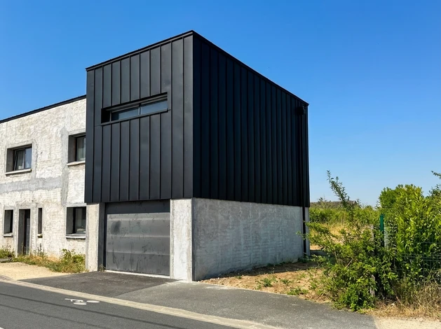 Ouvrier couvreur travaillant sur toiture ardoise d'une maison traditionnelle en pierre