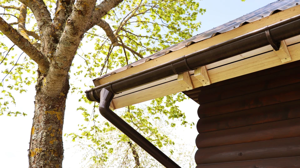 Ouvrier en équipement de sécurité haute visibilité installant une toiture métallique ondulée sur charpente industrielle au coucher du soleil