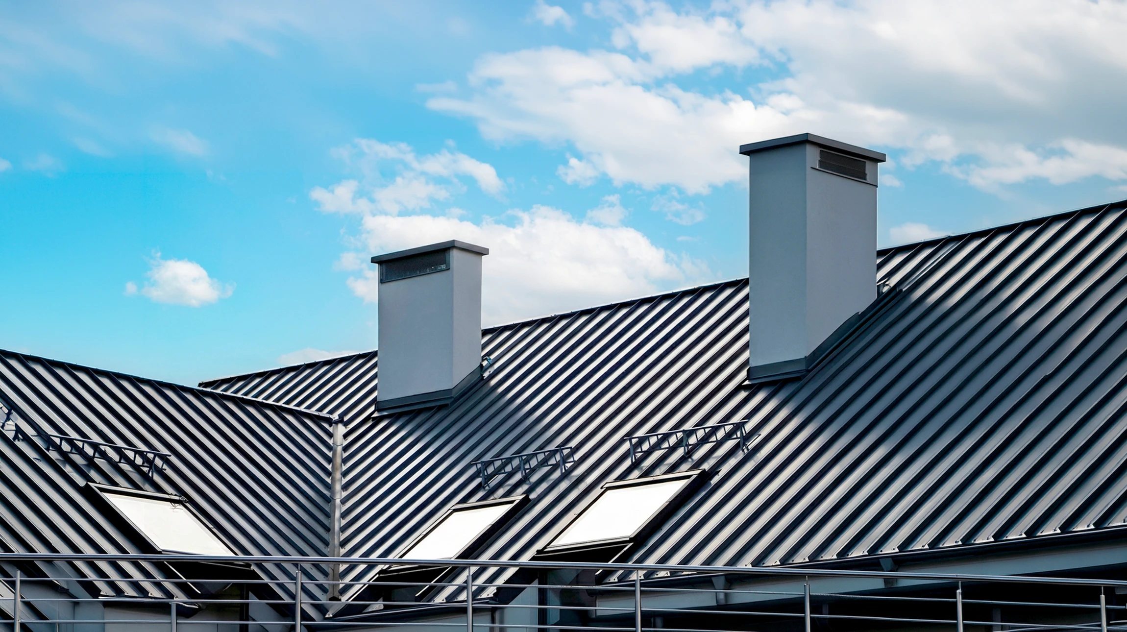 Ouvrier en casque de sécurité rouge installant une gouttière blanche sur une maison avec toiture en tuiles ondulées roses-beiges