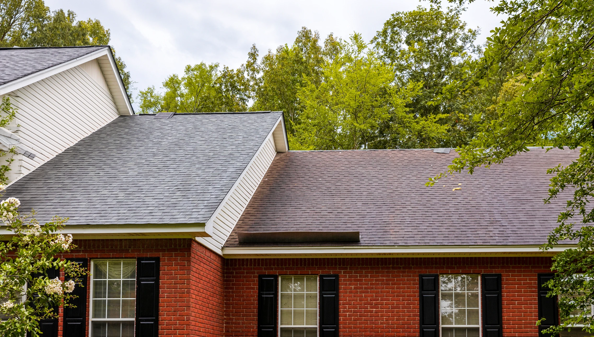 Chantier de couverture en cours avec ouvriers installant des tuiles terre cuite rouge sur charpente bois