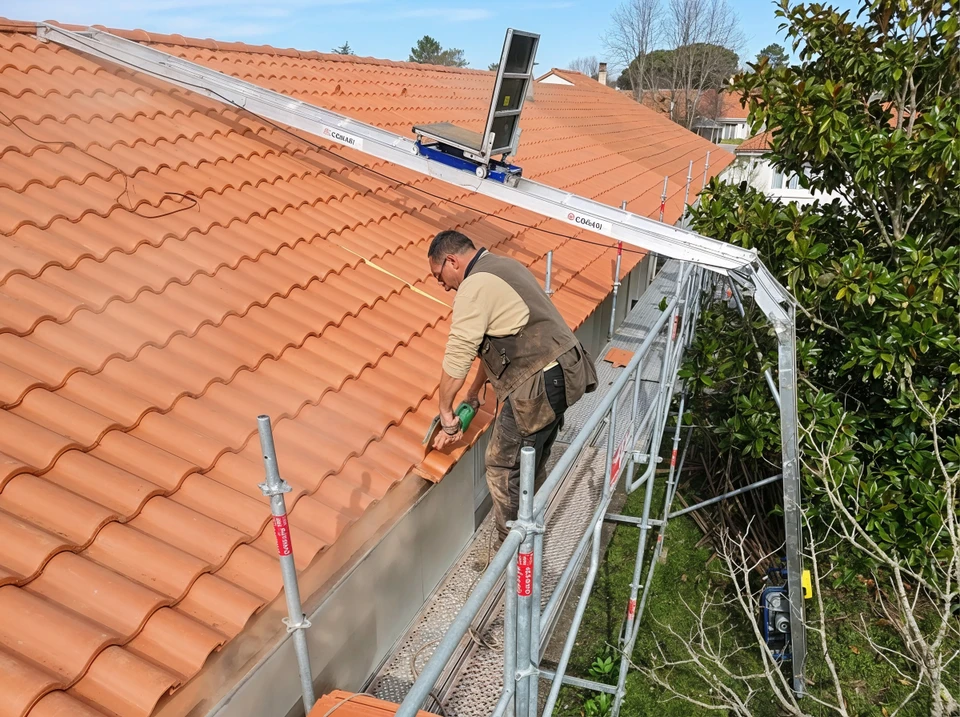 Photographie en plein jour d'une maison résidentielle avec une toiture récemment rénovée ou neuve, en excellent état, présentant des tuiles rouges ou terracotta brillantes et uniformes. La toiture doit être claire et nette, sans mousse, sans tuiles endommagées, incarnant la solidité et la protection. Le ciel doit être partiellement visible en arrière-plan. L'image doit transmettre la sécurité, la durabilité et le bon entretien du bâtiment.