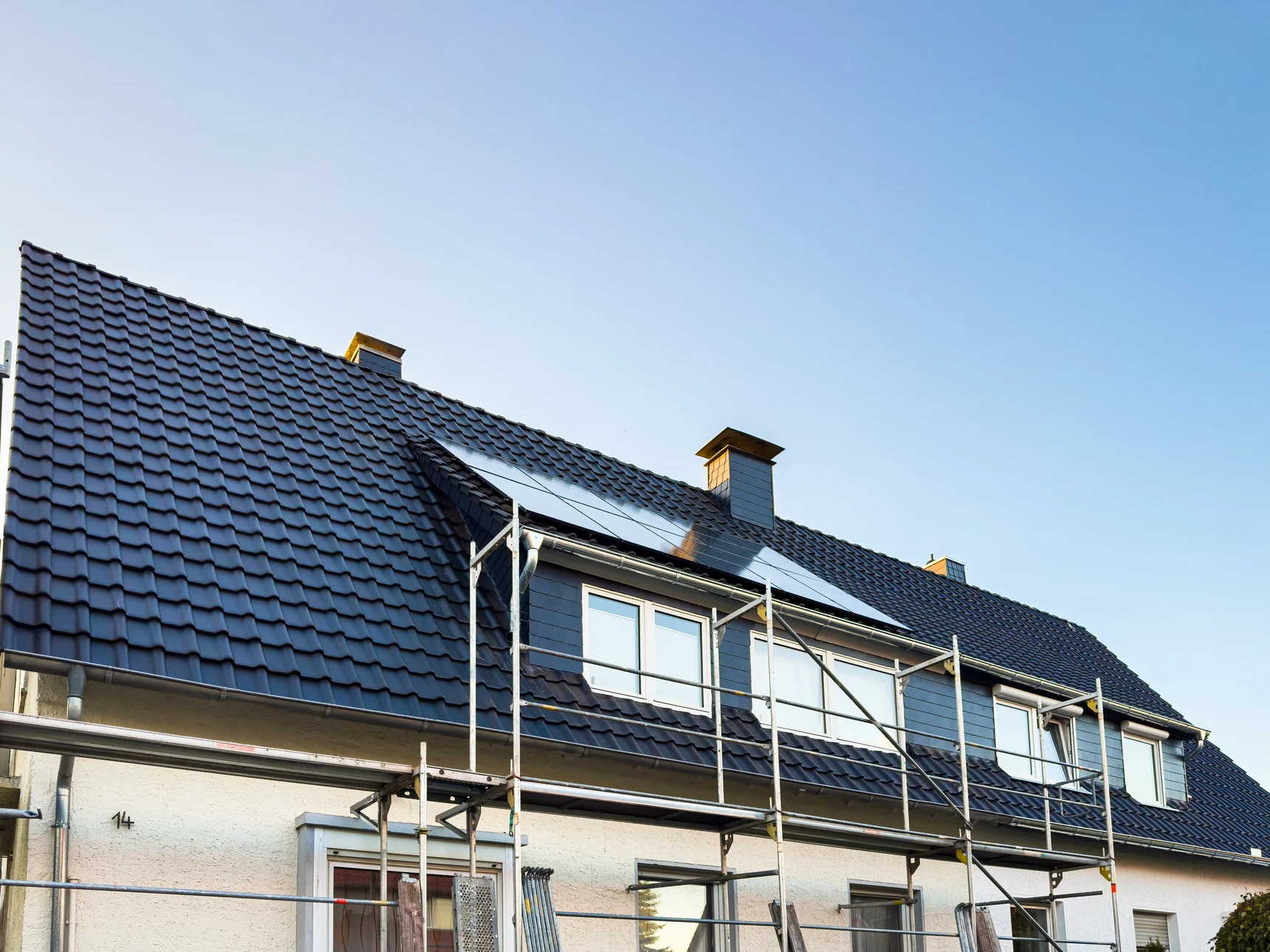 Toiture - ouvrier du bâtiment debout sur un toit le recouvrant de tuiles